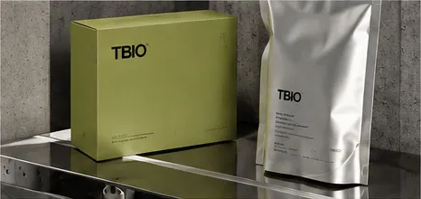 A citron TBIO box and a silver pouch on a steel shelf.